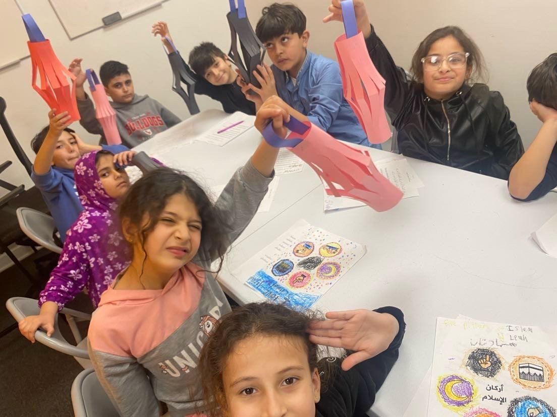 Elementary students proudly displaying handmade Ramadan lantern crafts in class