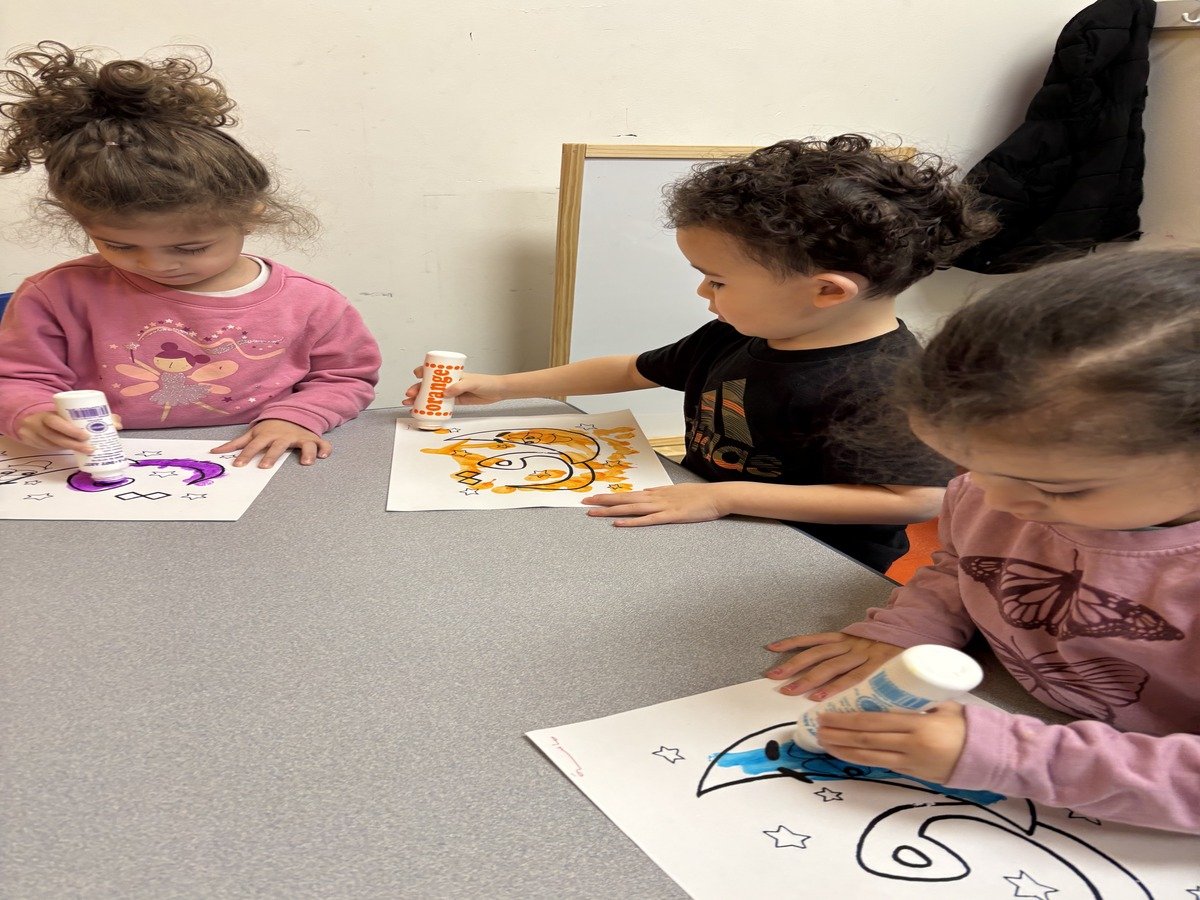 Young children engaged in creative coloring and glue art activities during class time
